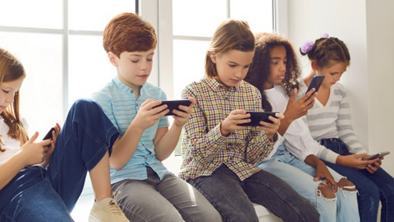 Fünf Kinder schauen auf ihr Smartphone