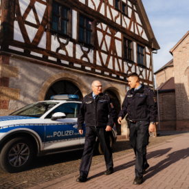 Streifenwagen und zwei Beamte vor altem Rathaus in Schifferstadt. 