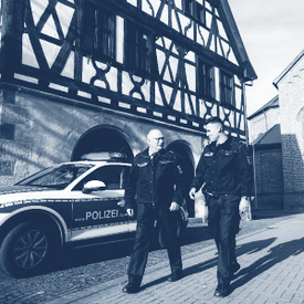 Streifenwagen und zwei Beamte vor altem Rathaus in Schifferstadt. 