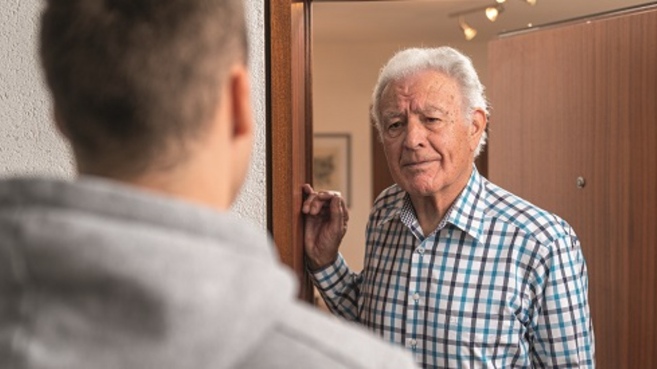 Ein Mann steht an der Wohnungstür einen Senioren