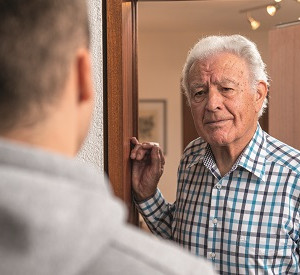Ein Mann steht an der Wohnungstür einen Senioren