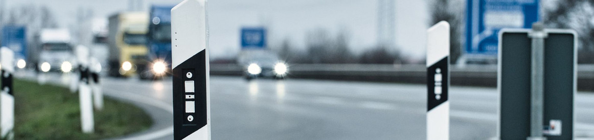 Nahaufnahme zweier Katzenaugen am Fahrbahnrand einer Autobahn