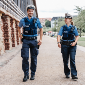 Polizeibeamter und Polizeibeamtin laufen Streife am Gradierbau. 