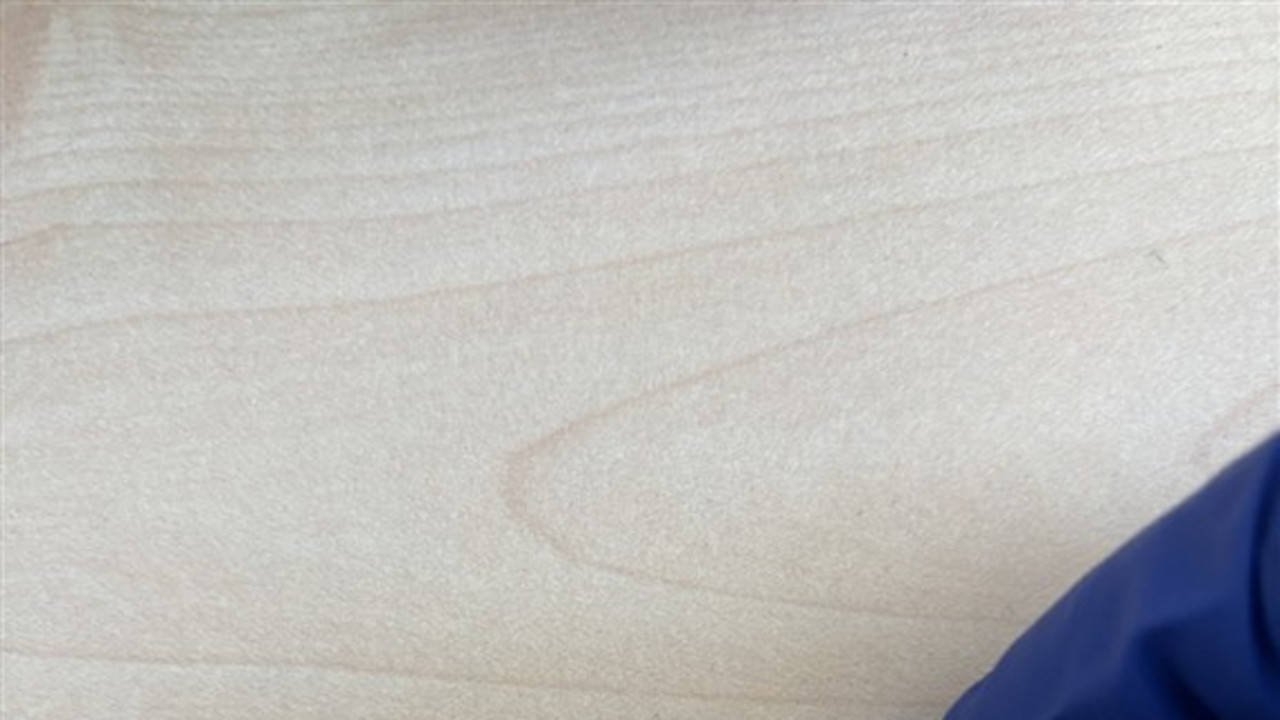 Zwischen zwei Fingern in blauem Handschuh wird Fläschchen einer Parfümprobe gehalten.