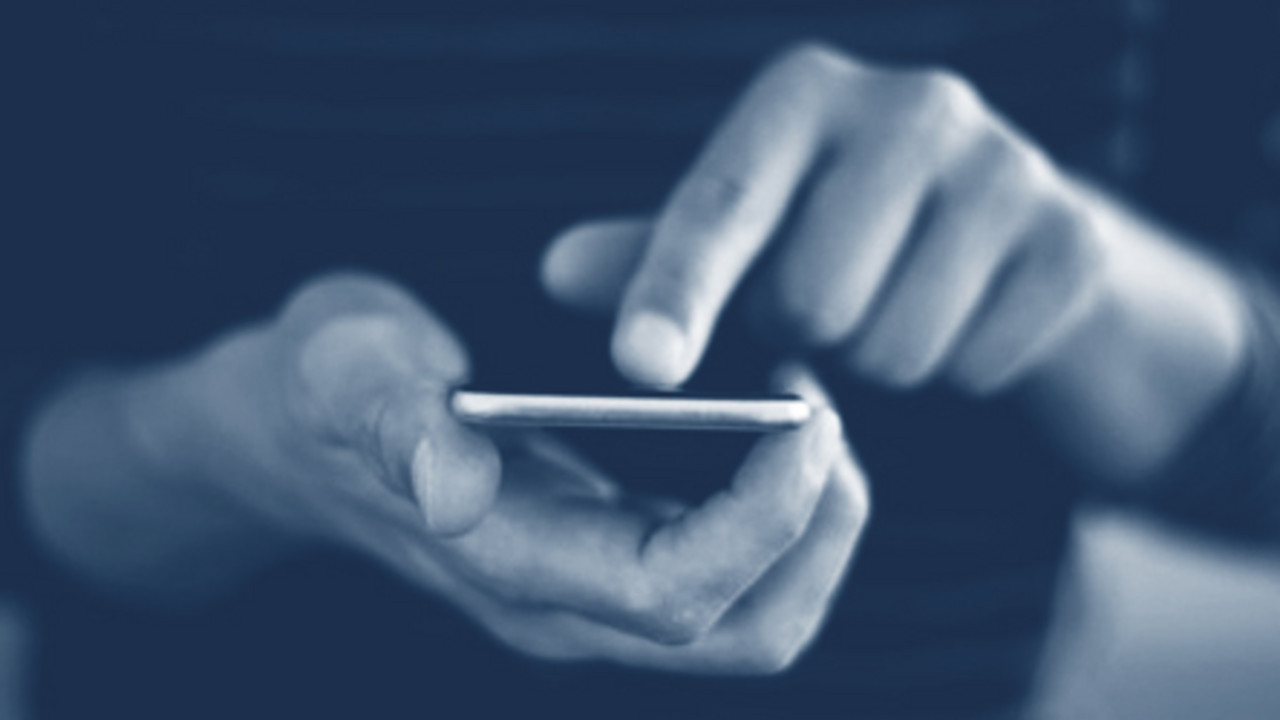 Männliche Person tippt etwas auf ein Handy ein