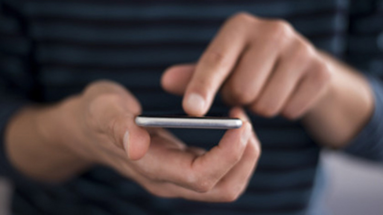 Männliche Person tippt etwas auf ein Handy ein