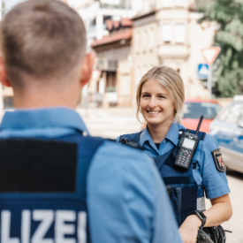 Polizeibeamtin im Gespräch mit Kollegen. 