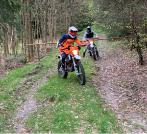 Ein unbekannter Motorradfahrer mit orangefarbenen Oberteil im Wald