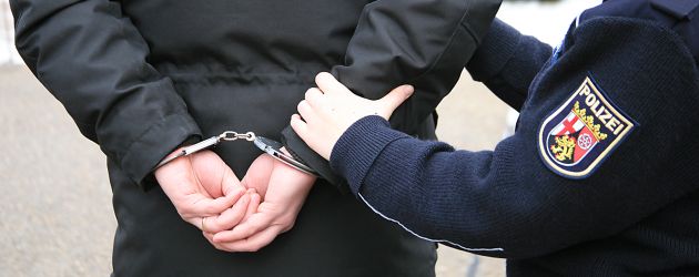 Täter wird in Handschellen von Polizistin abgeführt