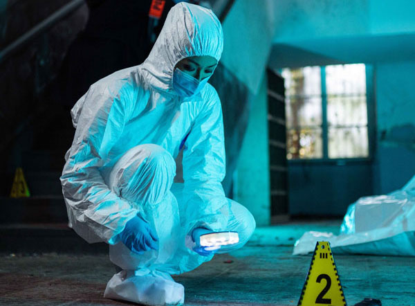 Forensikerin bei der Tatortarbeit im Schutzanzug mit Spurensicherung und Beweisanalyse