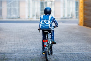 Kind mit Ranzen auf Rücken fährt mit dem Fahrrad