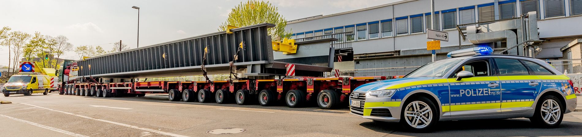 Schwerlasttransport mit Begleitfahrzeug und Streifenwagen